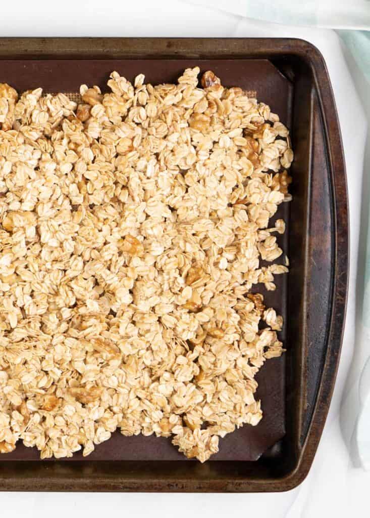 best homemade granola with raisins and dried cranberries on baking sheet before cooking
