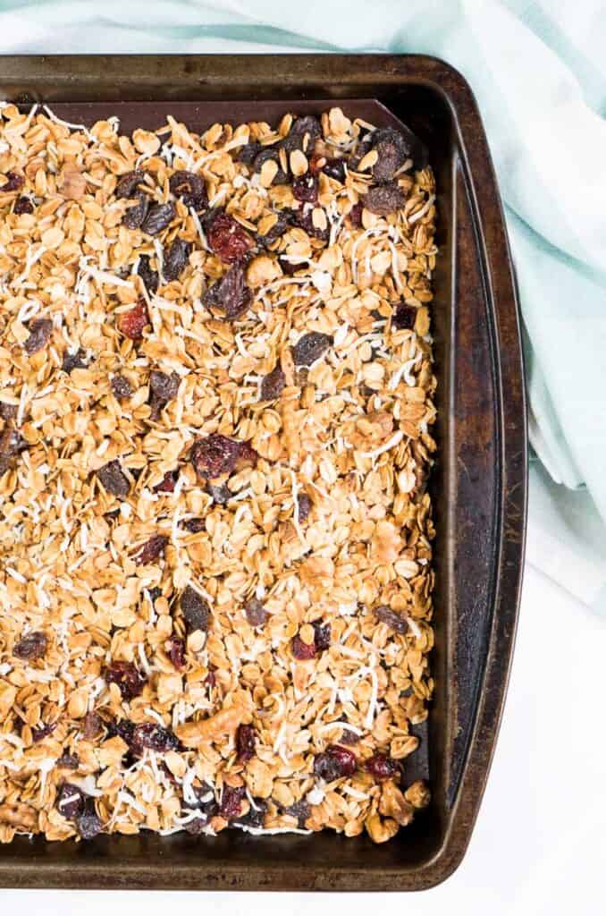 homemade granola with raisins and dried cranberries on baking sheet