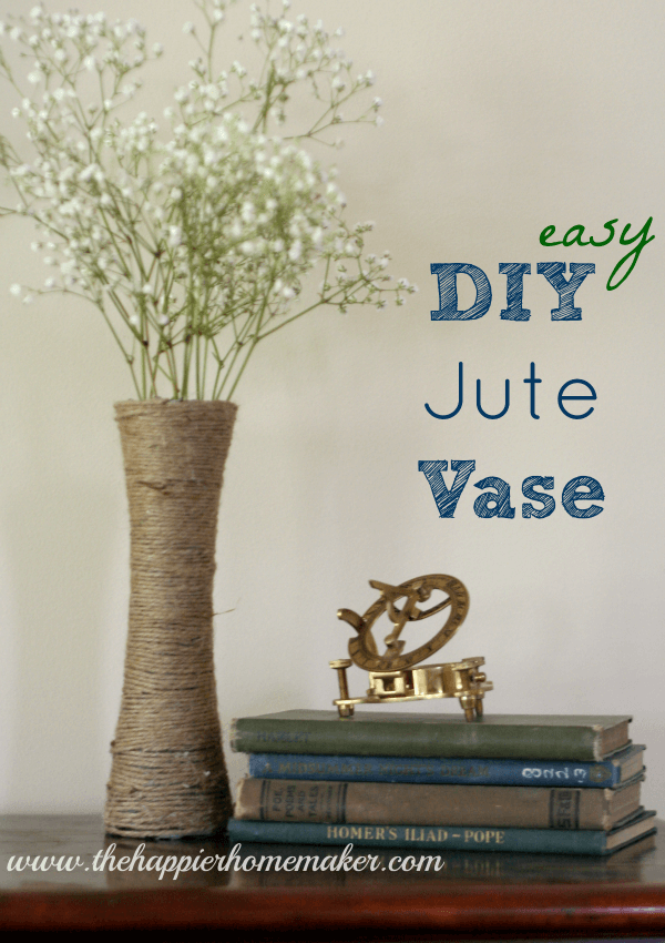 A DIY jute wrapped vase with small white flowers next to a books and a compass 