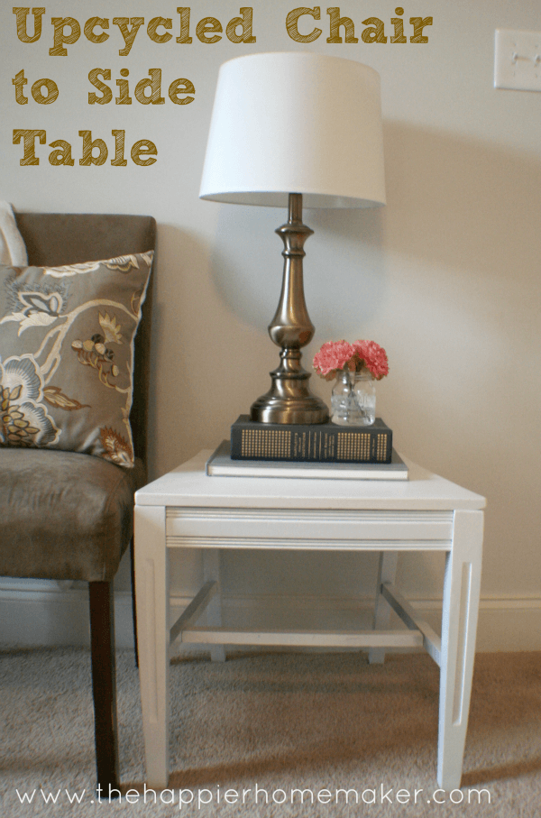 A close up of a white, up-cycled chair to side table  with a lamp and flowers on it