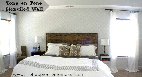 A tone on tone stenciled wall with a bedroom set in front of it