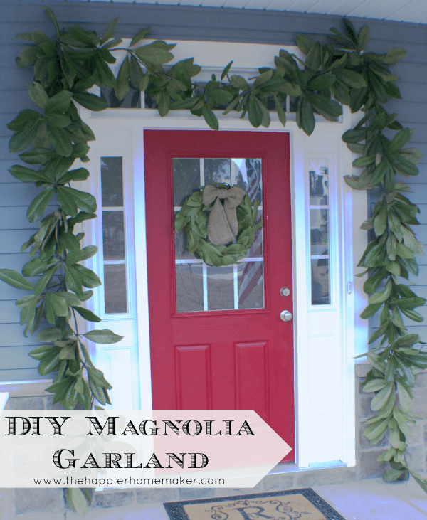 A close up of a red door with magnolia garland around it