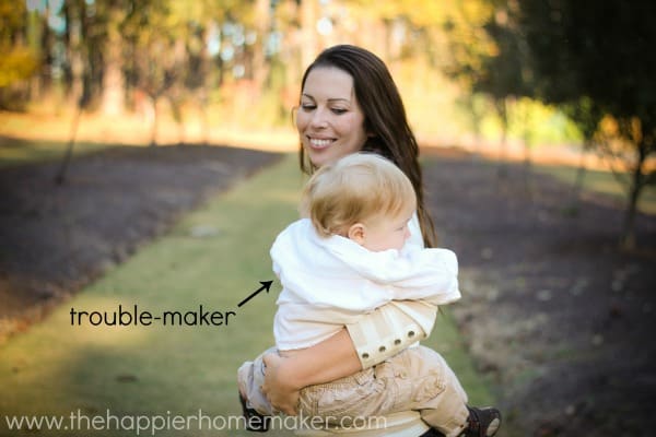 A woman holding a toddler with the words "trouble maker" for the toddler