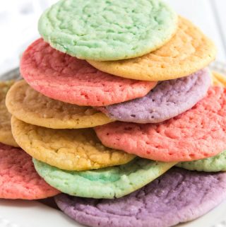 rainbow colored kool-aid cookies stacked on white plate