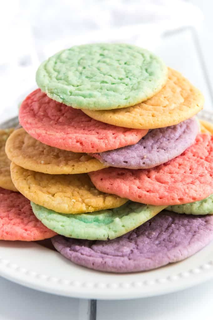 rainbow colored kool-aid cookies stacked on white plate
