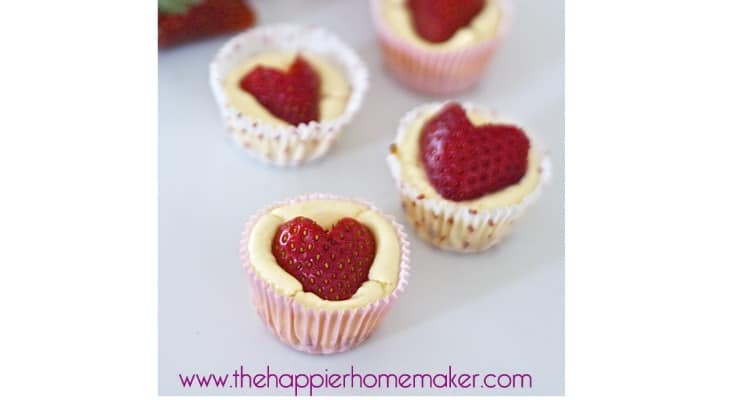 A close up of strawberry heart mini cheesecake bites topped with strawberries cut like hearts on top