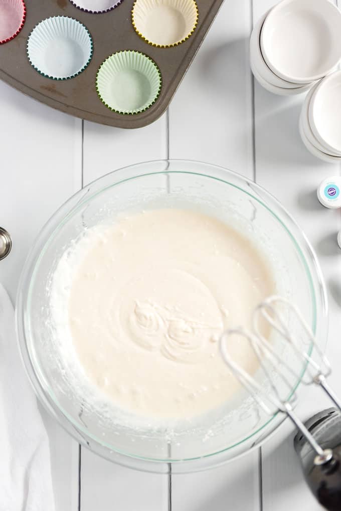 cupcake batter in glass bowl with mixer nearby 