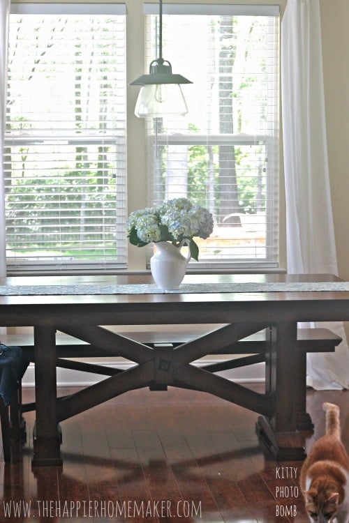 A white vase of hydrangea flowers sitting on a wood table