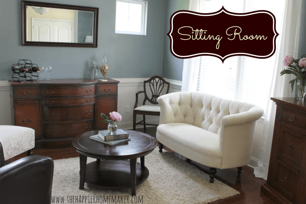 A sitting room with a white sofa, chair, coffee table and brown server