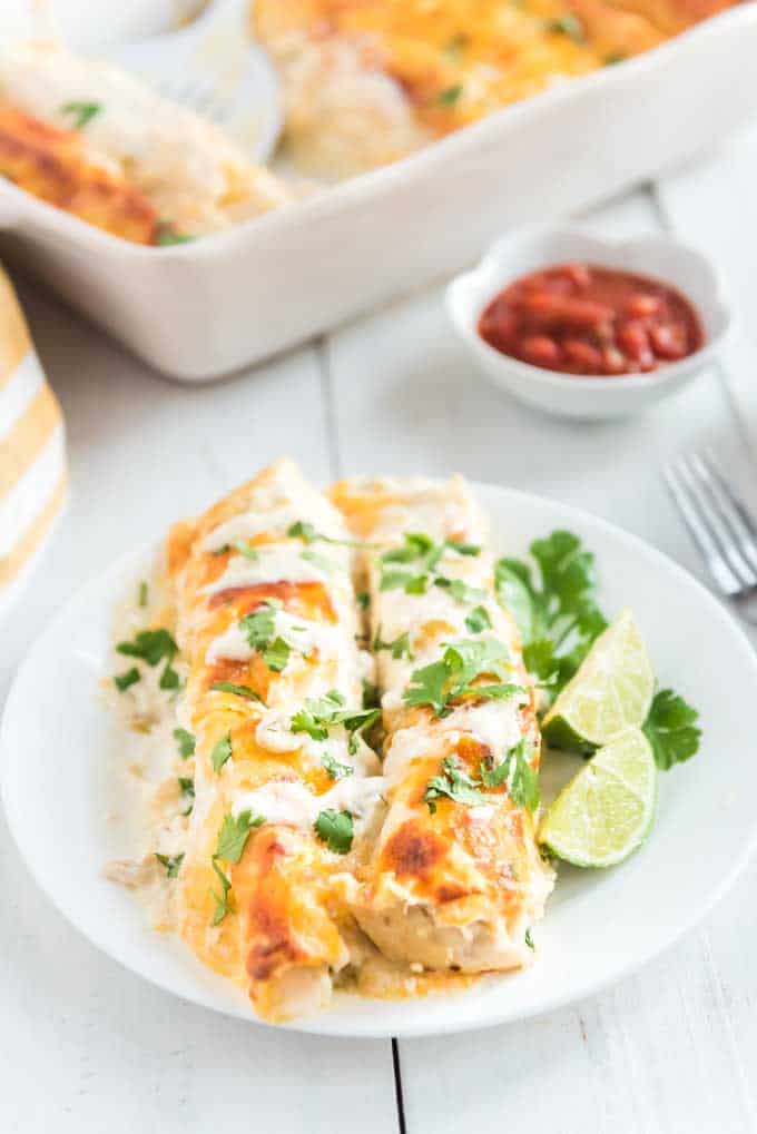 two white chicken enchiladas on a white plate 