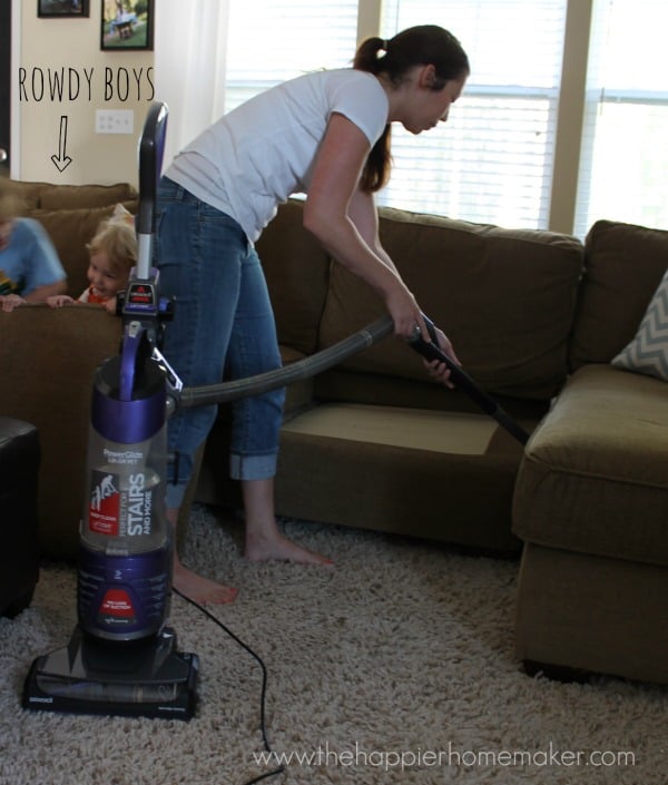 A woman vacuuming in-between sofa cushions 