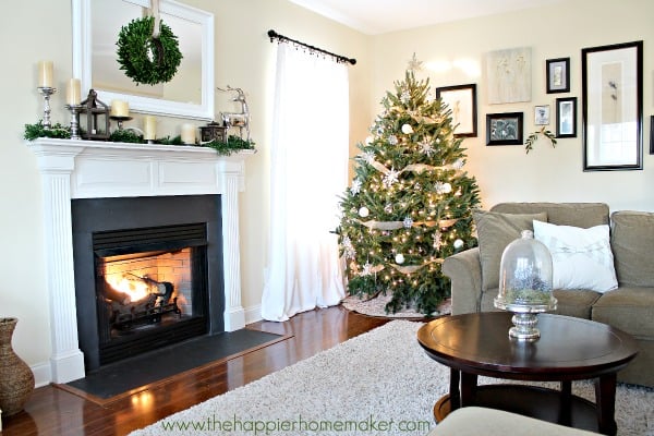 A lit fireplace in a living room with a Christmas tree in the corner