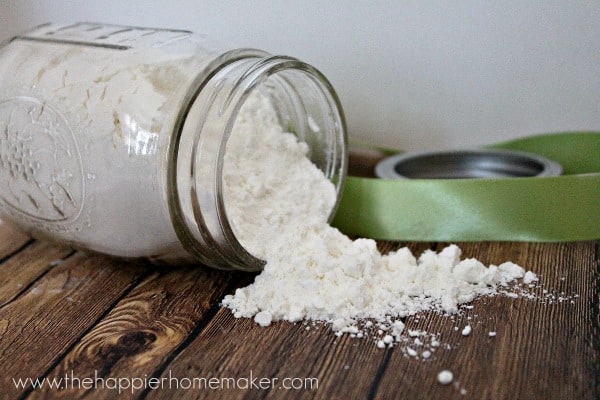 A mason jar on its side with homemade milk bath spilled on a wood table