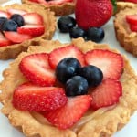 A close up of berry tarts topped with sliced strawberries and blueberries