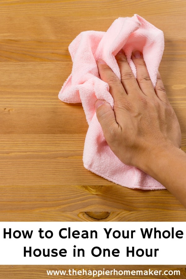 A hand wiping down a table with a pink cleaning cloth