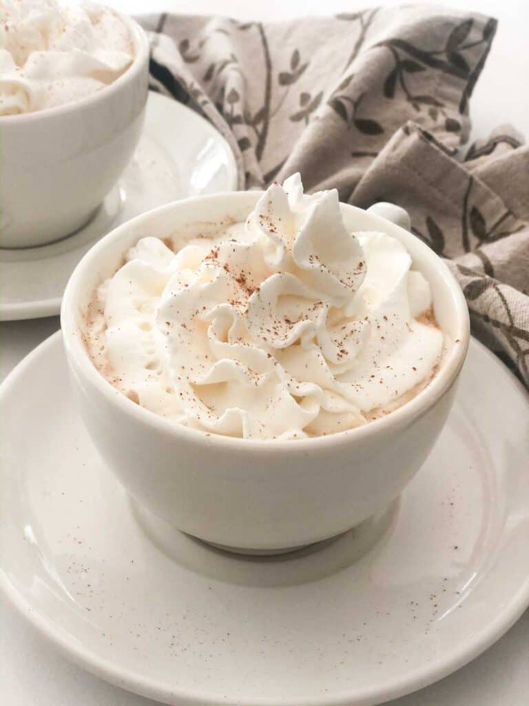 pumpkin spice latte with whipped cream in white mug on saucer