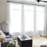 large living room window with white curtains and yellow rug