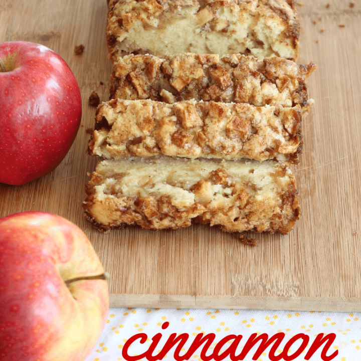 Cinnamon apple bread sliced on a cutting board next to two apples