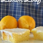 A close up of lemon loaf in front of lemons and a blue and white checkered cloth