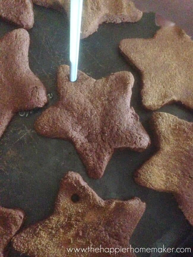 poking hole in cinnamon dough ornaments on baking sheet