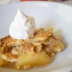 apple dump cake on white plate with whipped cream on top