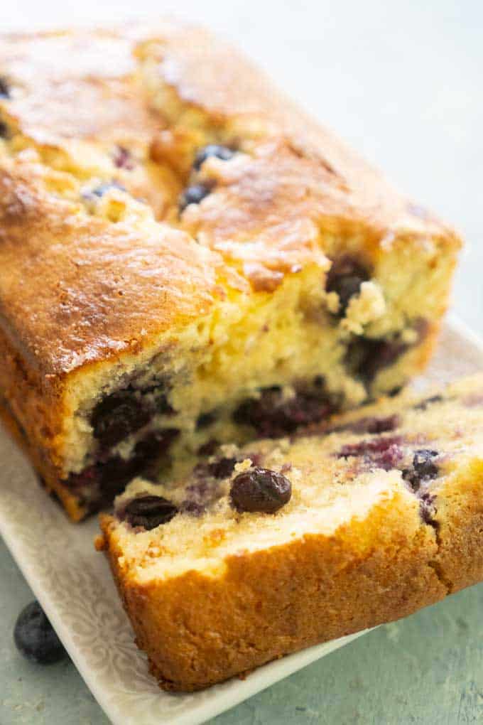 blueberry bread on a white plate with one slice cut off