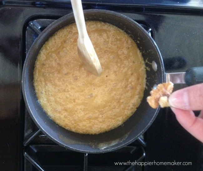 cooking toffee in saucepan with hand holding walnut above