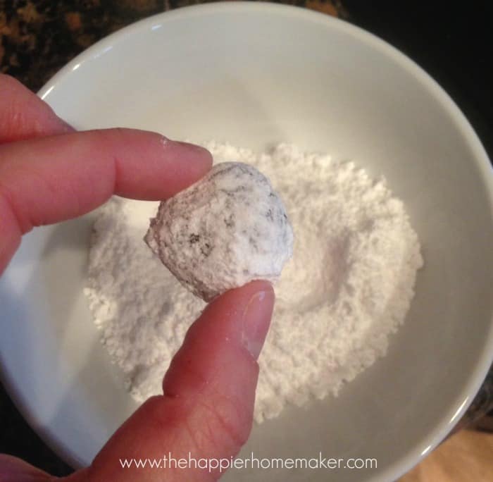 dusting chocolate crinkle cookies in powdered sugar