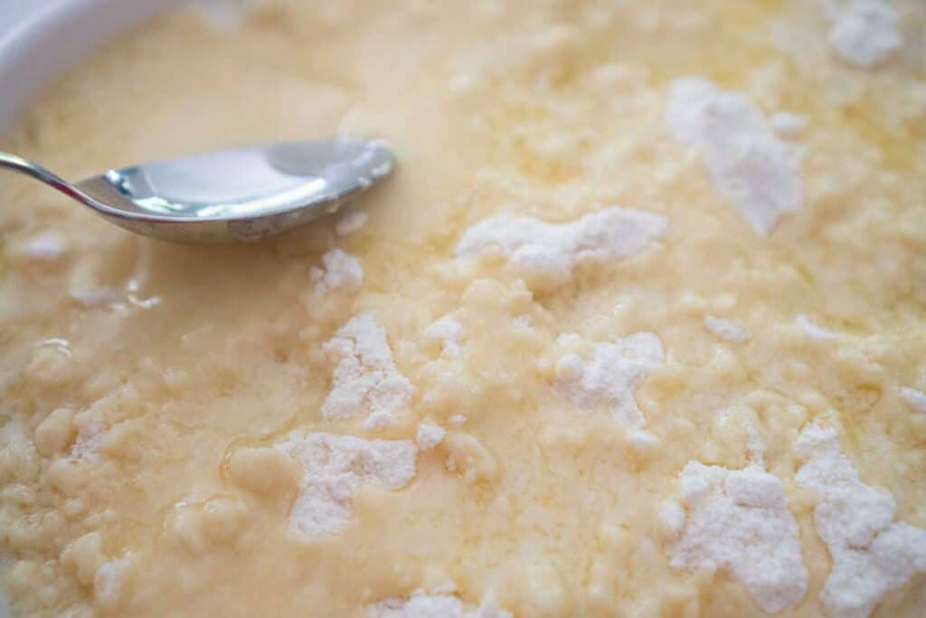 spoon spreading melted butter over cake mix for dump cake