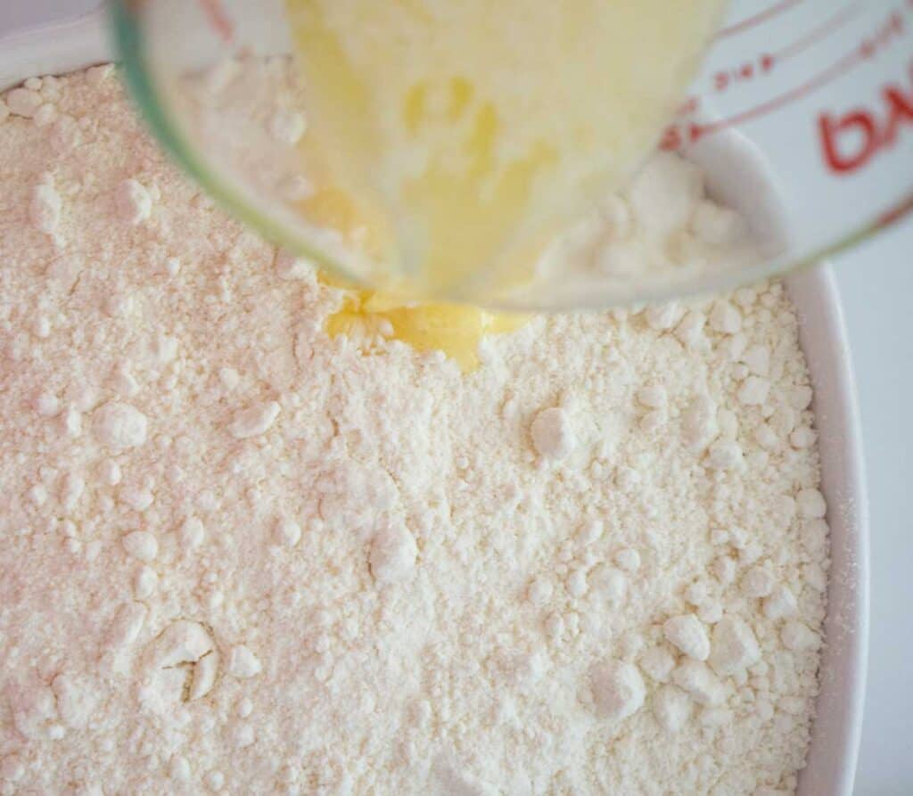 overhead view of pouring butter over cake mix