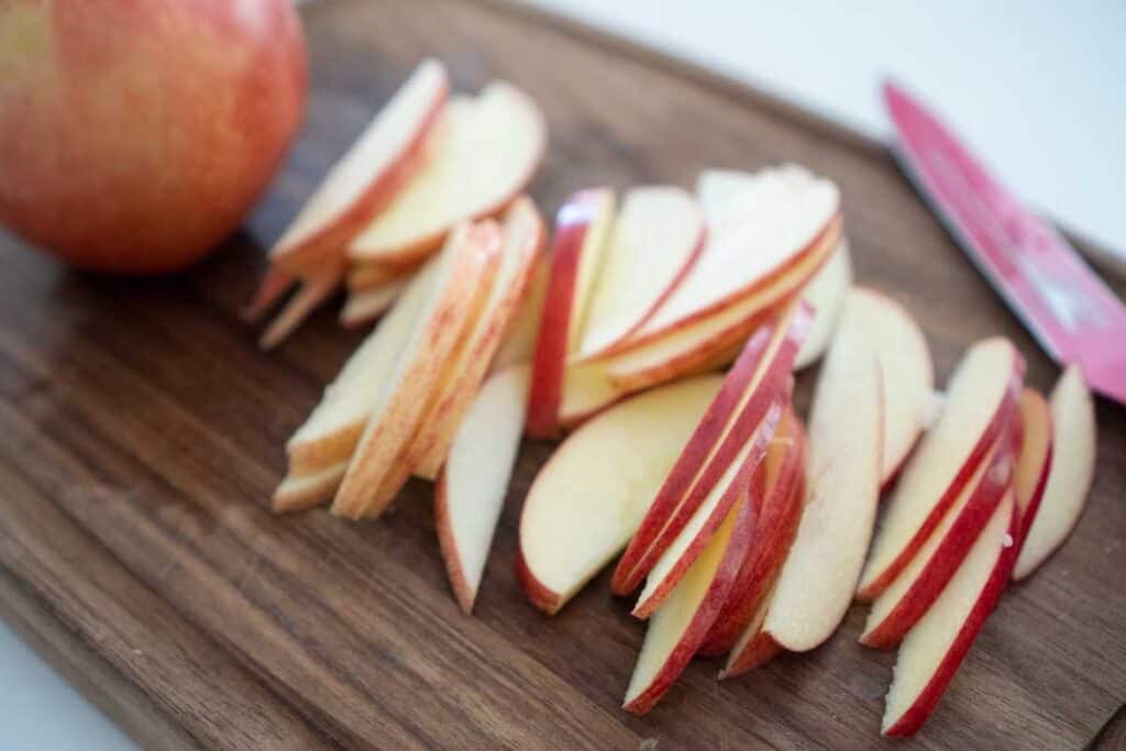 thinly sliced apples on wood cutting board