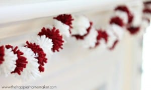 A close up of Valentine's Day mini pom pom garland hanging on a white mantel