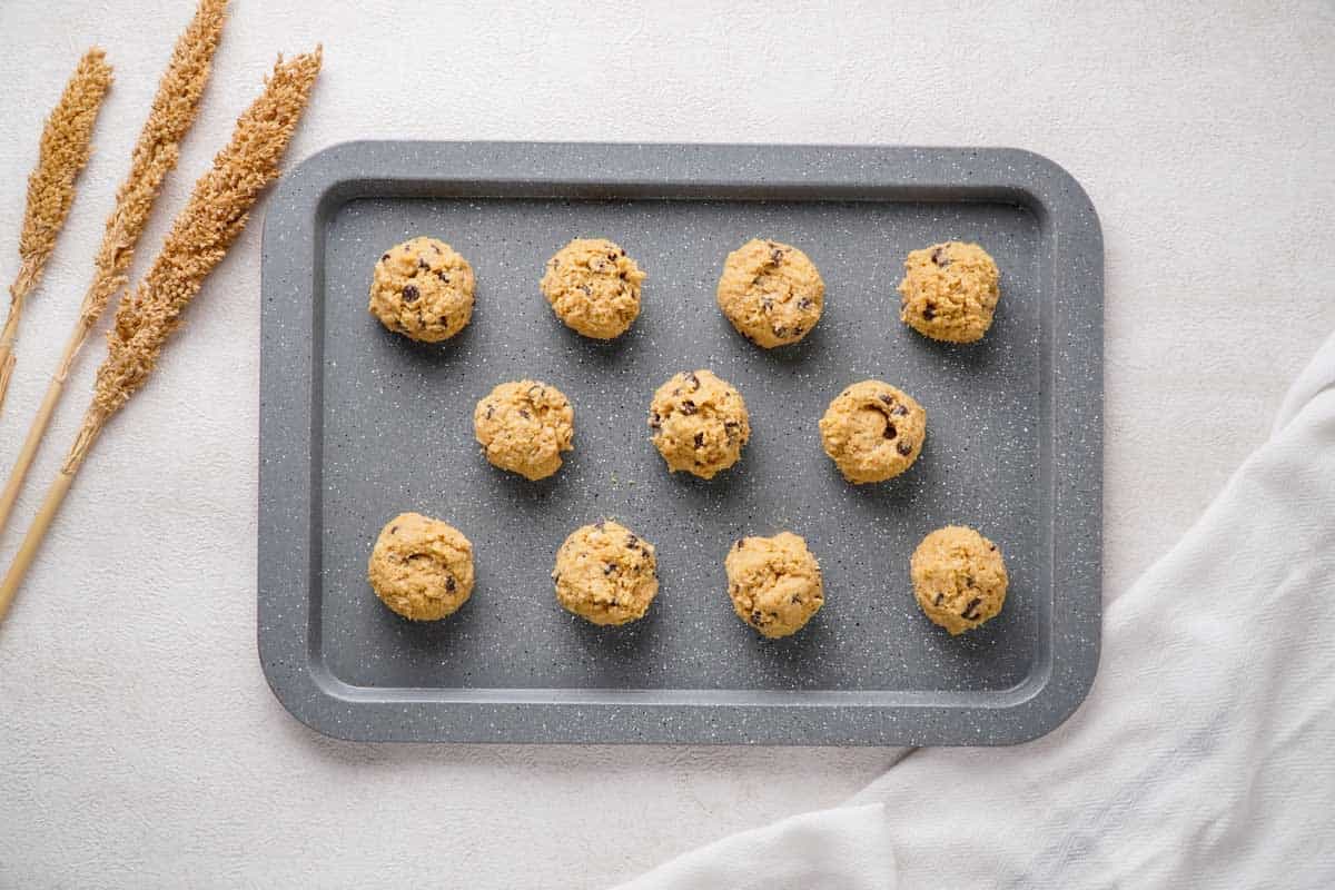overhead view of chocolate chip oatmeal cookie dough balls on baking sheet before baking