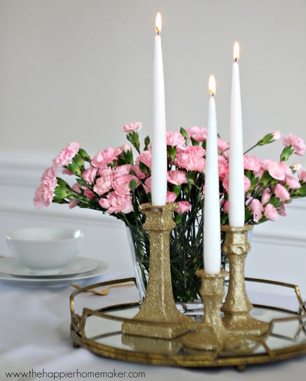 Three no shed glitter candlesticks in front of flowers on a white table