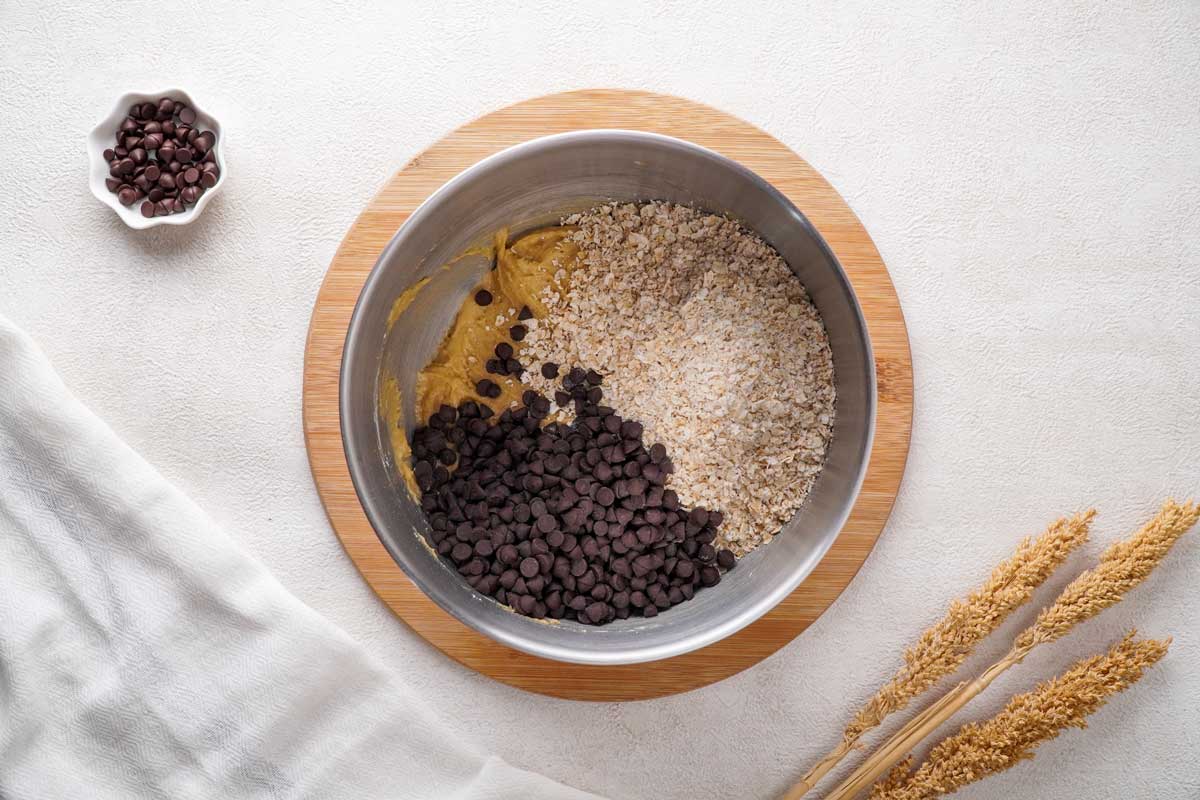overhead view of mixing bowl with oatmeal chocolate chip cookie dough ingredients