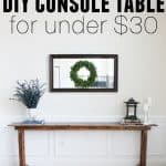 A DIY console table with greenery, lantern and candlesticks on it