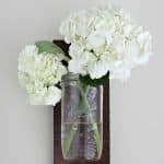 Two hydrangea flowers in a DIY mason jar wall vase