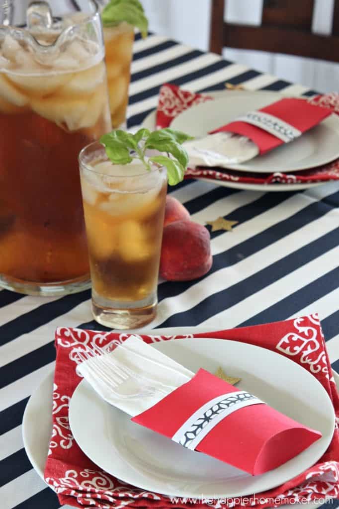 table with striped navy and white tablecloth and red and white place settings with iced tea pitcher and glass