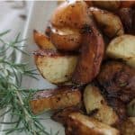 A close up of balsamic roasted potatoes next to rosemary