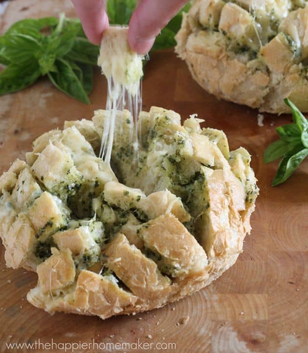 A close up picture of pesto cheesy pull apart bread with one piece being pulled away