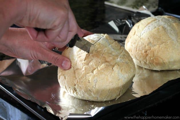 An in-process picture of someone making pesto cheesy pull apart bread by cutting it