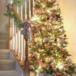 A brightly lit and decorated Christmas tree next to a stairwell