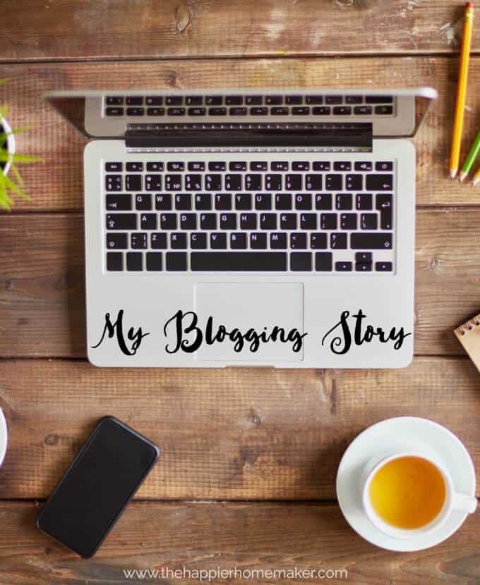 An above picture of a laptop with the words "my blogging story" written in cursive on the bottom of the computer with a cup of tea, pencils and paper nearby 