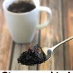 A spoonful of brownie mix in front of a white coffee cup on a wood table