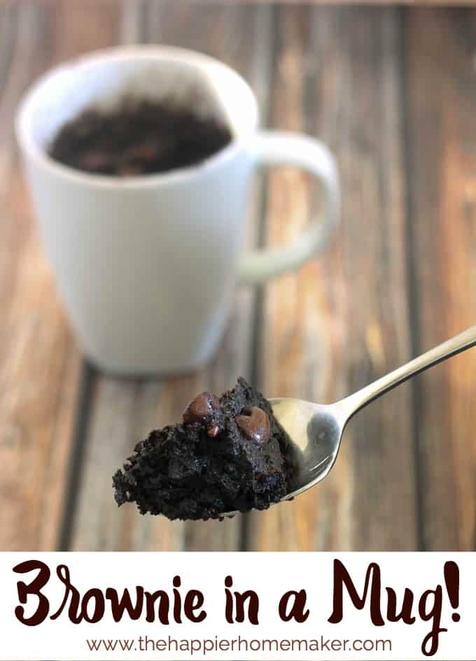 A spoonful of brownie mix in front of a white coffee cup on a wood table