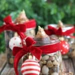 A close up of three mason jars tied with red ribbon and Christmas ornaments filled with DIY paperwhite  bulbs