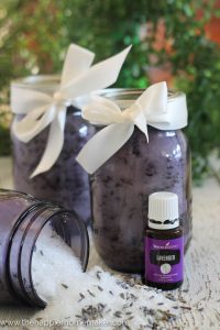 A close up of three jars of lavender bath salts with a lavender oil in front