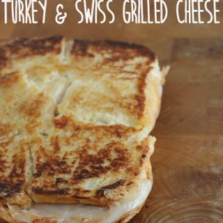 A close up of an inside out grilled Turkey Swiss sandwich on a wooden cutting board