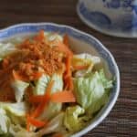 close up of salad in porcelain bowl with carrot ginger dressing on top