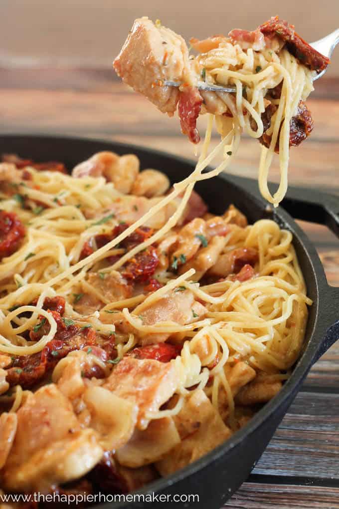 forkful of Tuscan chicken pasta in a cast iron pan